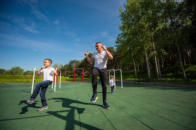 Blanke man en twee jongens doen oefeningen buitenshuis Vader en zonen trainen op het sportveld