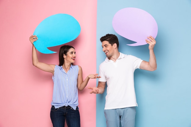 blanke man en vrouw met copyspace banners voor aankondiging, geïsoleerd over kleurrijke muur