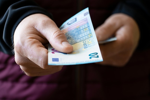 Foto blanke man geeft euro papiergeld twintig rekeningen closeup