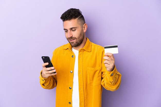 Blanke man geïsoleerd op paars kopen met de mobiele telefoon met een creditcard