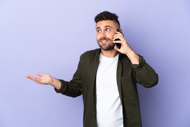 Blanke man geïsoleerd op paarse muur een gesprek met de mobiele telefoon met iemand houden