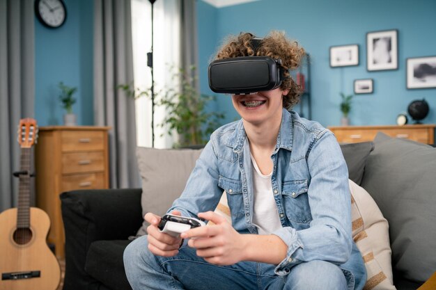 Blanke man geniet van virtual reality-bril terwijl hij op de bank zit, gelukkige jonge man met vr-headset