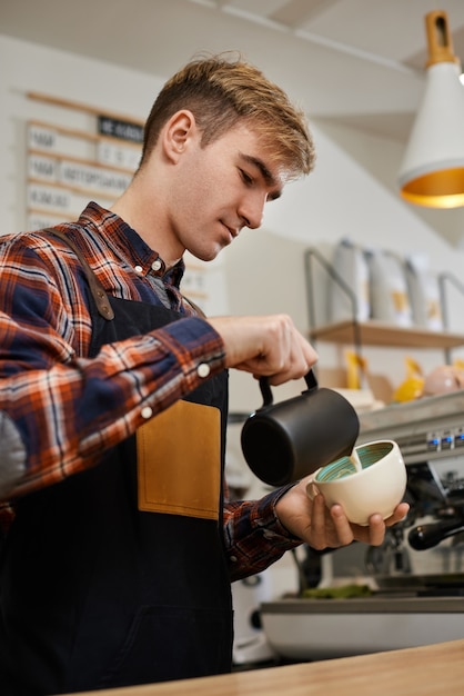 Blanke man giet hete melk in koffie