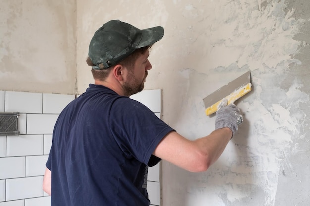 Blanke man heeft gips aangebracht om de scheuren in de muur te dichten Renovatie van flat