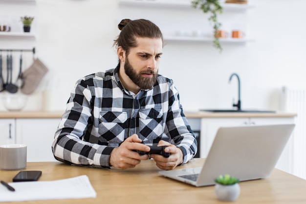 blanke man in een geruite shirt die een afstandsbediening gebruikt om videospelletjes te spelen