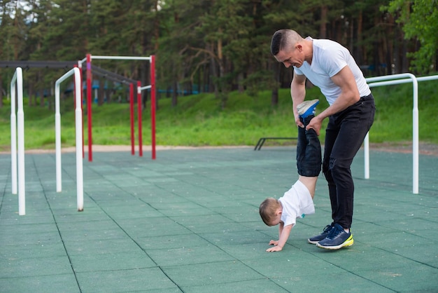 Blanke man leert zoon handstand op speelplaats