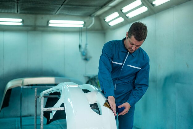 Blanke man maakt auto-onderdelen schoon voordat hij kleur spuit in reparatie monteur schilderwerkplaats