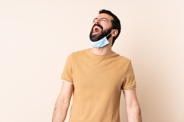 Blanke man met baard beschermen met een masker en handschoenen over muur lachen