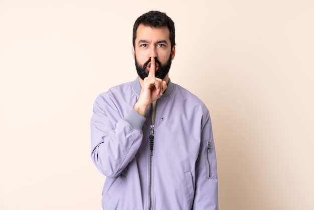 Blanke man met baard dragen van een jas over geïsoleerde achtergrond met een teken van stilte gebaar vinger in de mond steken