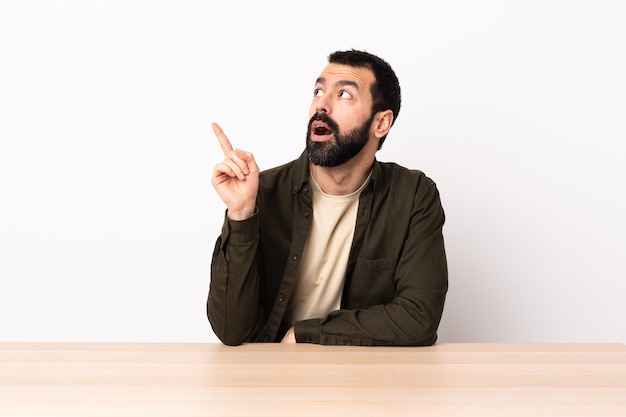 Blanke man met baard in een tafel denken een idee met de vinger omhoog.