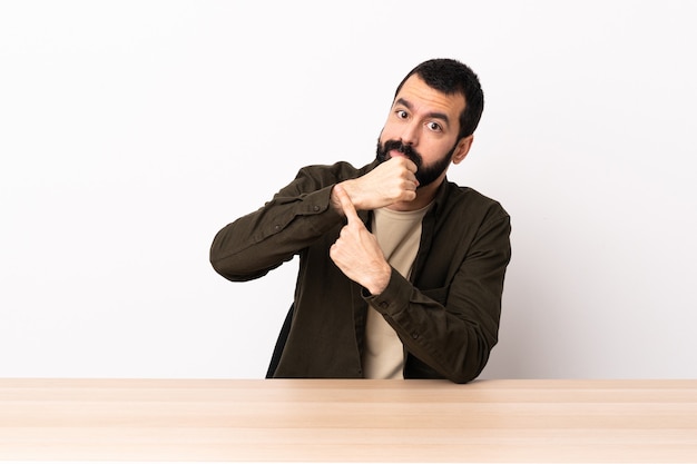 Blanke man met baard in een tafel die het gebaar maakt om te laat te zijn.