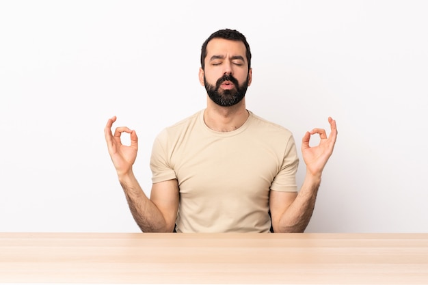 Blanke man met baard in een tafel in zen pose