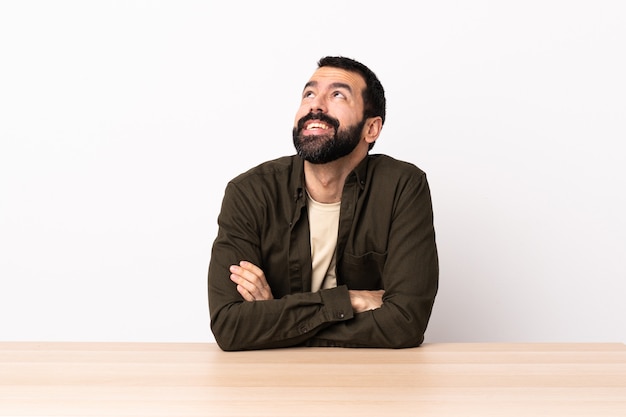 Blanke man met baard in een tafel opzoeken terwijl lachend.