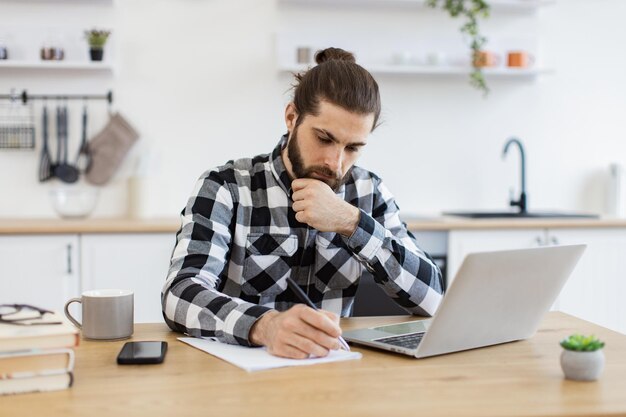 blanke man met een geruite shirt die op een document schrijft