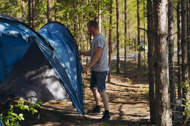 blanke man met een hoed die een tent opstelt gezinscampingconcept