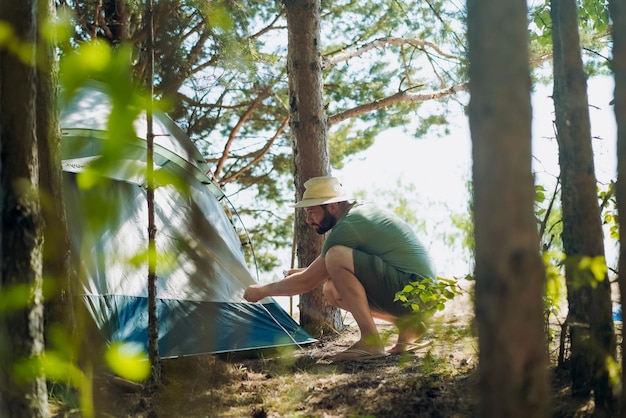 Blanke man met een hoed die een tent opzet Familie camping concept