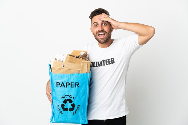 Blanke man met een recyclingzak vol papier om te recyclen geïsoleerd op een witte achtergrond met verrassingsuitdrukking