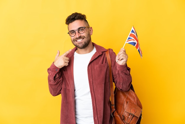 Blanke man met een vlag van het Verenigd Koninkrijk geïsoleerd op geel met een duim omhoog gebaar