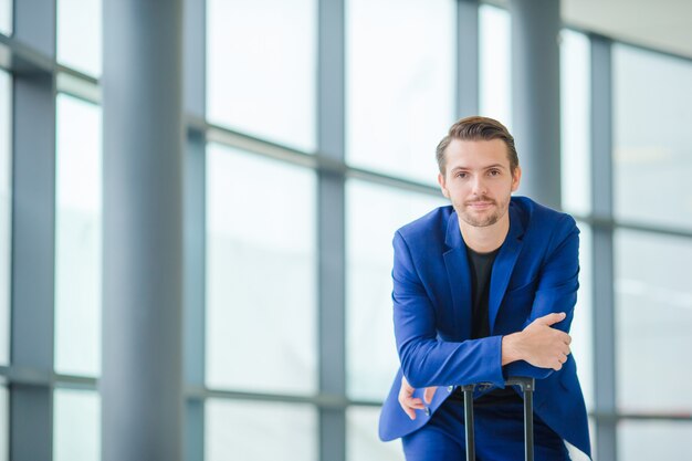 Blanke man met mobiel op de luchthaven tijdens het wachten op instappen