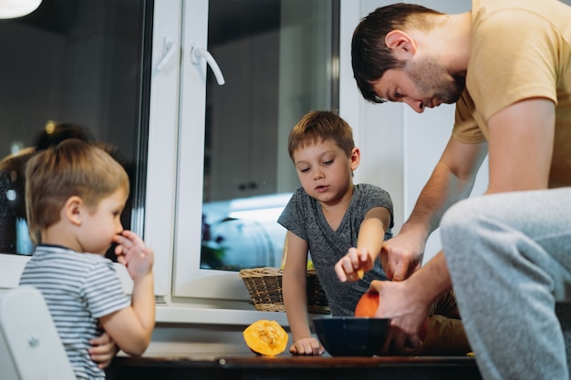 Blanke man met zijn zonen die ogen uitsnijden op een pompoen om traditionele Jack-lantaarn te maken. . Hoge kwaliteit foto