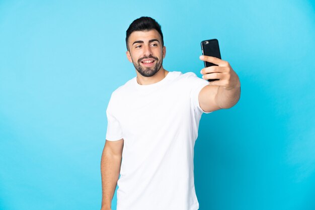 Blanke man over geïsoleerde blauwe achtergrond een selfie maken