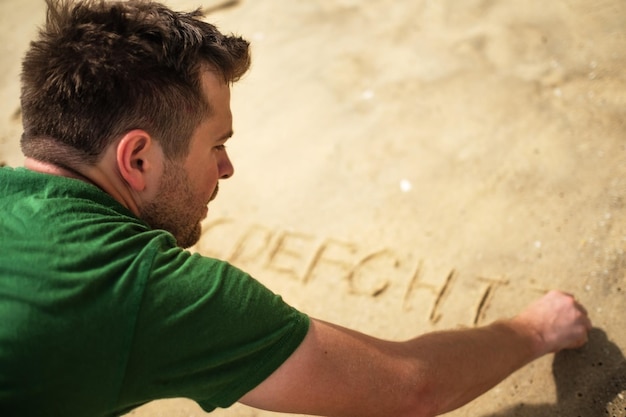 Blanke man schrijven op zand Alfabetletters