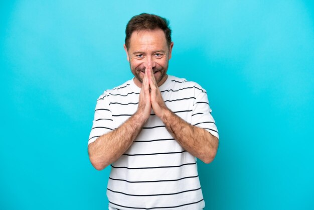 Foto blanke man van middelbare leeftijd geïsoleerd op blauwe achtergrond houdt handpalm bij elkaar persoon vraagt om iets