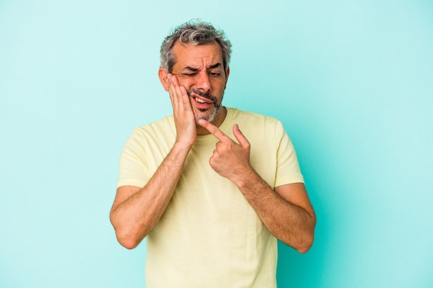 Blanke man van middelbare leeftijd geïsoleerd op blauwe achtergrond met een sterke tandenpijn, kiespijn.