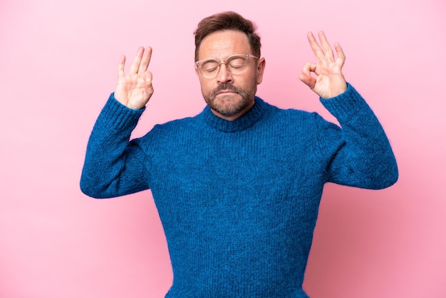 Blanke man van middelbare leeftijd geïsoleerd op roze achtergrond in zen pose