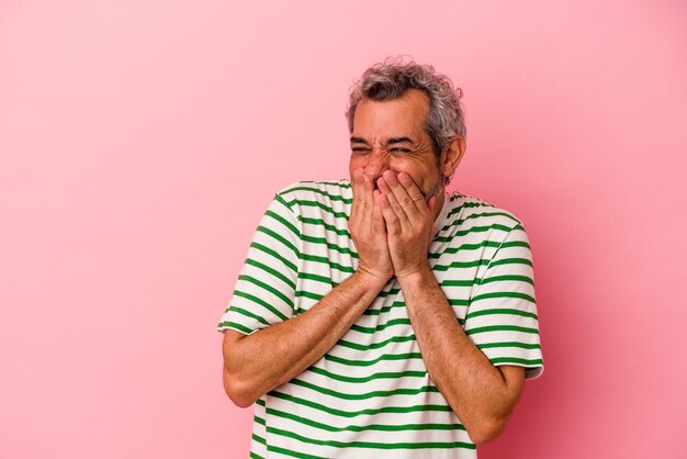 Blanke man van middelbare leeftijd geïsoleerd op roze achtergrond lachen om iets, mond bedekken met handen.