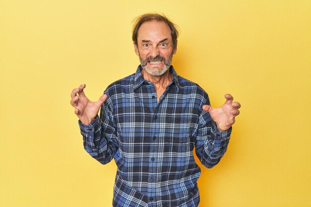 Foto blanke man van middelbare leeftijd in gele studio schreeuwend van woede