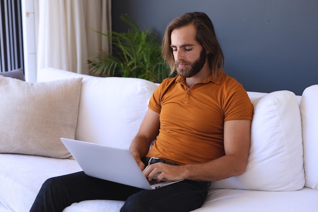 Blanke man zit op de bank met behulp van laptop. thuis blijven tijdens de quarantaine-lockdown.