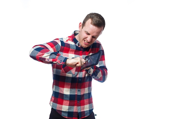 Blanke mannelijke freelancer, reparateur, krast de beschermende film op het tabletscherm en verwijdert deze. het dragen van een overhemd. Emotioneel portret. Geïsoleerd op witte achtergrond