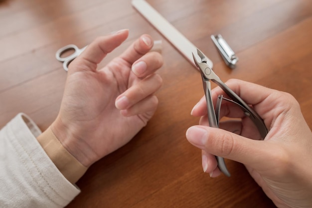 Blanke meisje maakt zichzelf een manicure thuis close-up jonge vrouw gebruikt nagelknipper