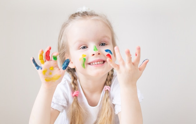 Blanke meisje schilderij met kleurrijke handen schildert thuis Vroege educatie Voorbereiding op school Voorschoolse ontwikkeling Kinderen Spel