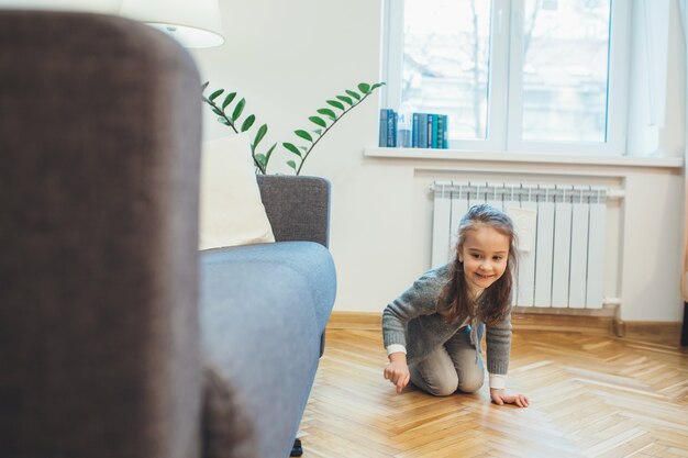 Blanke meisje speelt verstoppertje is op zoek naar iemand onder het bed