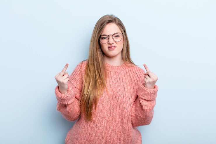 Foto blanke roodharige vrouw die zich provocerend, agressief en obsceen voelt en de middelvinger omdraait met een rebelse houding