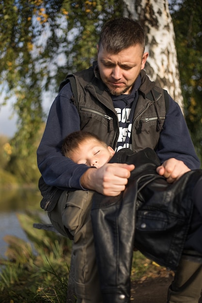 Blanke vader die lacht terwijl hij met haar slapende zoon buiten loopt