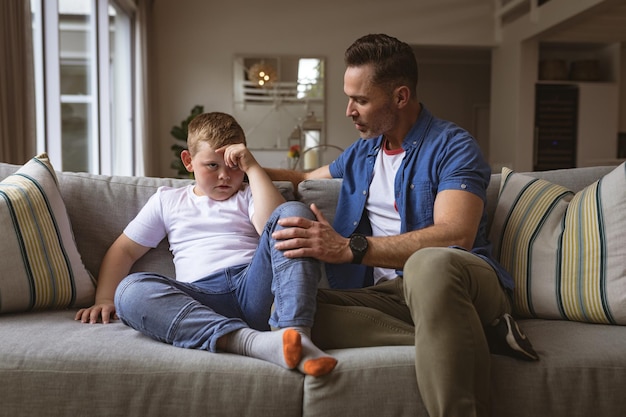 Blanke vader die zijn zoon uitscheldt terwijl hij thuis op de bank zit