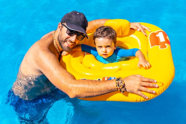 Blanke vader speelt in de zomer met zijn zoon met een gele dobber in het zwembad