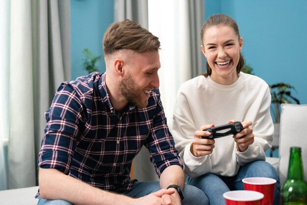 Foto blanke vrienden die thuis op de bank zitten en videogames spelen op de console van een vrolijke vrouw met