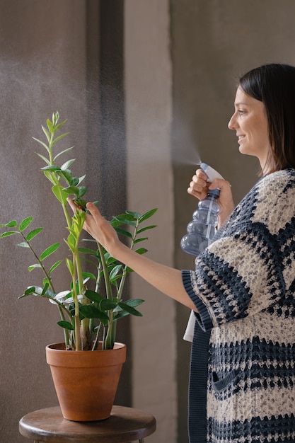 Foto blanke vrouw die bloemen water geeft en bevochtigt bloemen thuis planten water geven en verplanten