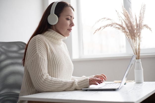 Blanke vrouw die geniet van muziek of podcast en smartphone vasthoudt Roodharige vrouw in modern kantoor