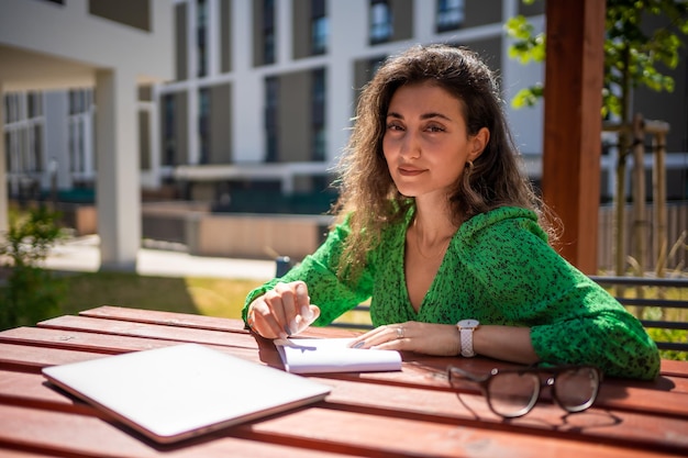 Blanke vrouw die ideeën tekent op een notitieboekje buiten kantoor