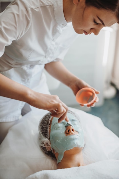 Blanke vrouw die ontspant terwijl ze een alginaatmasker op haar gezicht heeft in een spa salon schone huid schoonheid t...