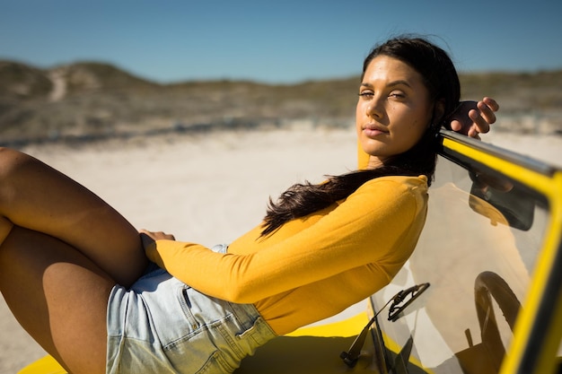 Blanke vrouw die op een strandbuggy ligt en naar de camera kijkt. strandvakantie tijdens een roadtrip in de zomervakantie.