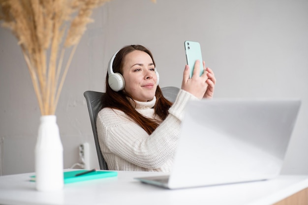 Blanke vrouw die selfie of videogesprek maakt Roodharige vrouw in modern kantoor