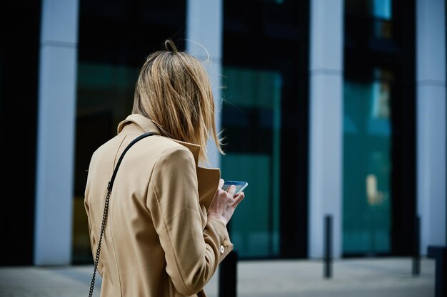 Blanke vrouw die smartphine gebruikt op stadsstraat