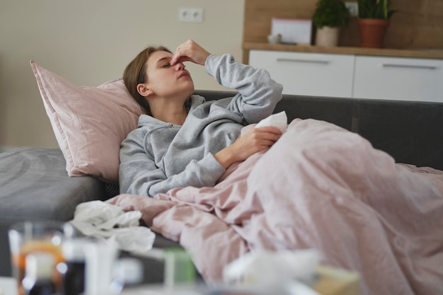 blanke vrouw die thuis op de bank ligt met griep
