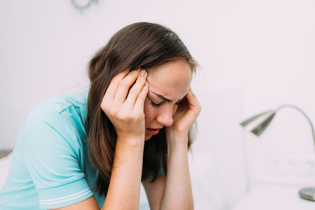 Blanke vrouw die thuis zit en last heeft van hoofdpijn.